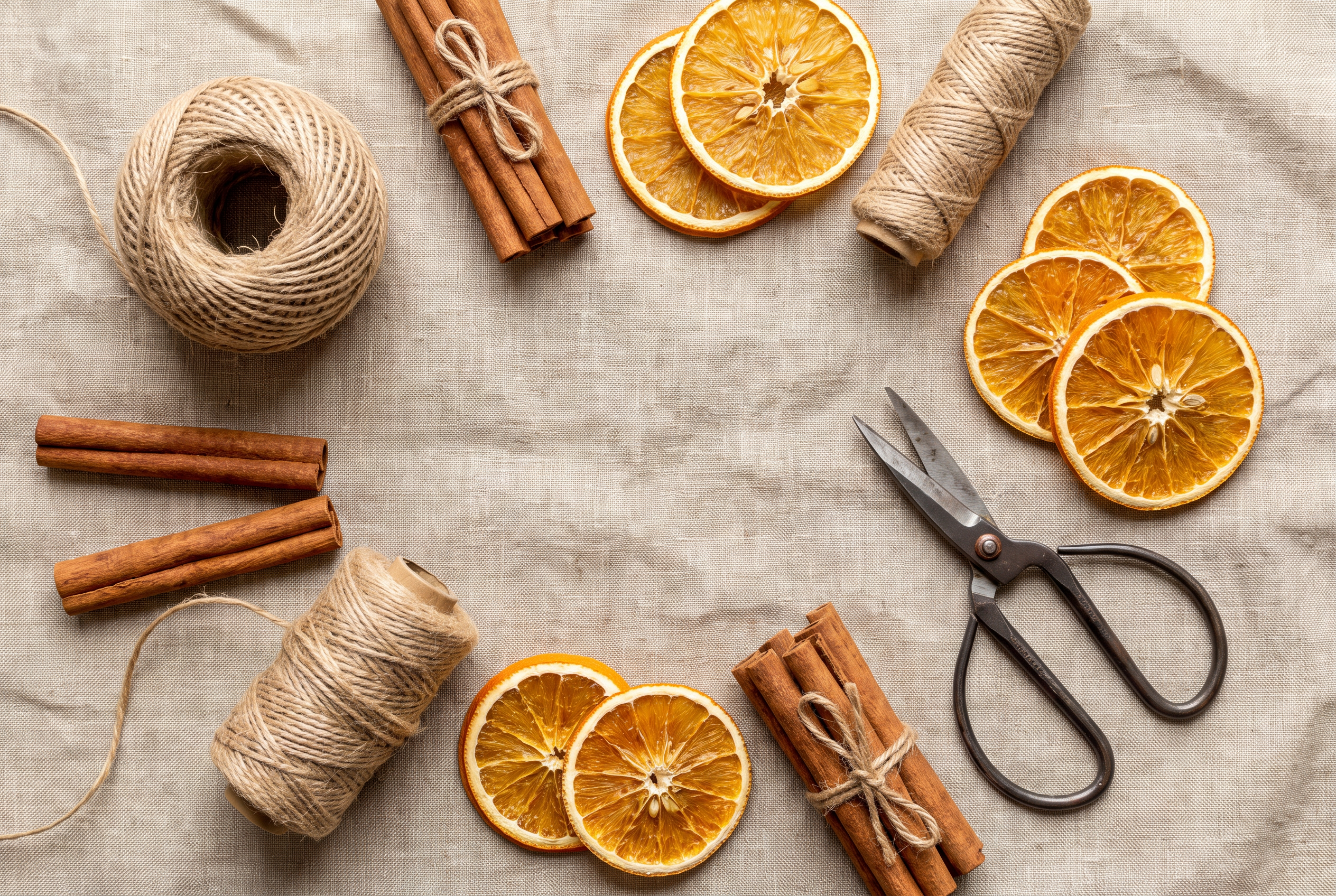 Cinnamon sticks, dried orange slices and twine laid out for a craft